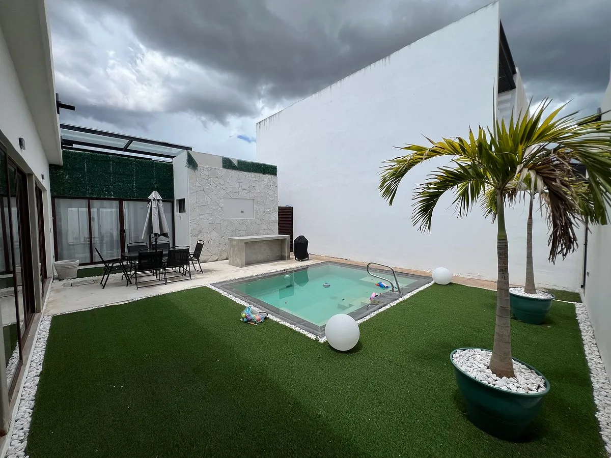 Patio trasero con alberca y área de jardín
